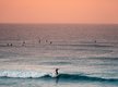 Eine Surferin surft im Weißwasser bei Sonnenuntergang